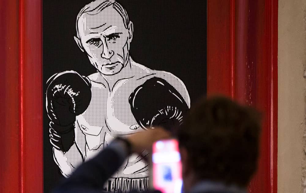A man takes a picture of an artwork depicting Russian President Vladimir Putin as boxing legend Muhammad Ali during the 