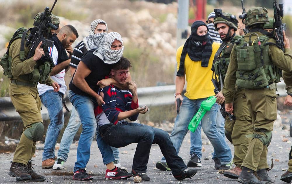 Undercover Israeli police officers and Israeli soldiers detain a wounded Palestinian demonstrator, being pulled up, during clashes near Ramallah, West Bank.