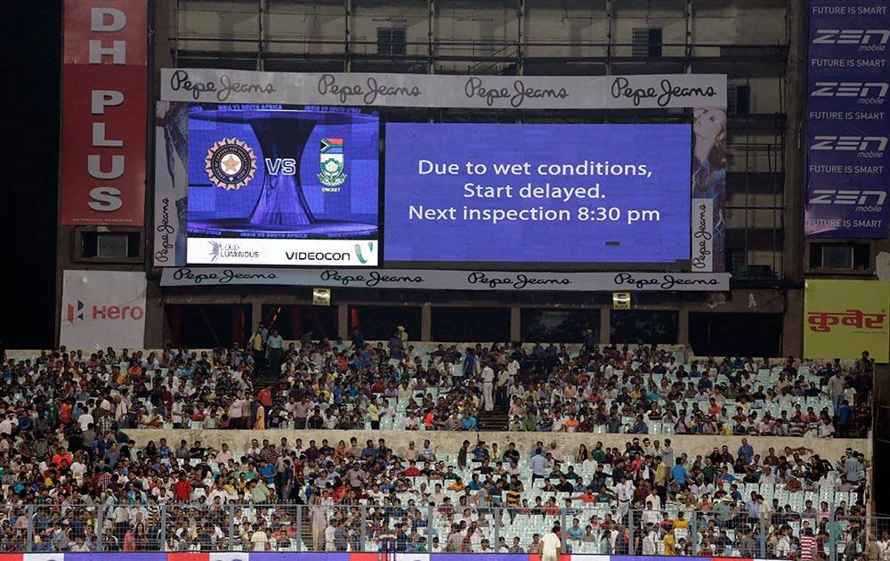 Cricket enthusiasts wait as an announcement flashes on an electronic board in Kolkata.