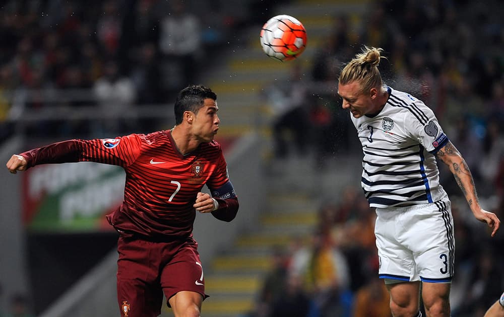 Portugal’s Cristiano Ronaldo, left, jumps for the ball with Denmark’s Simon Kjaer during the Euro 2016 qualifying group I soccer match between Portugal and Denmark at the Municipal Stadium in Braga.