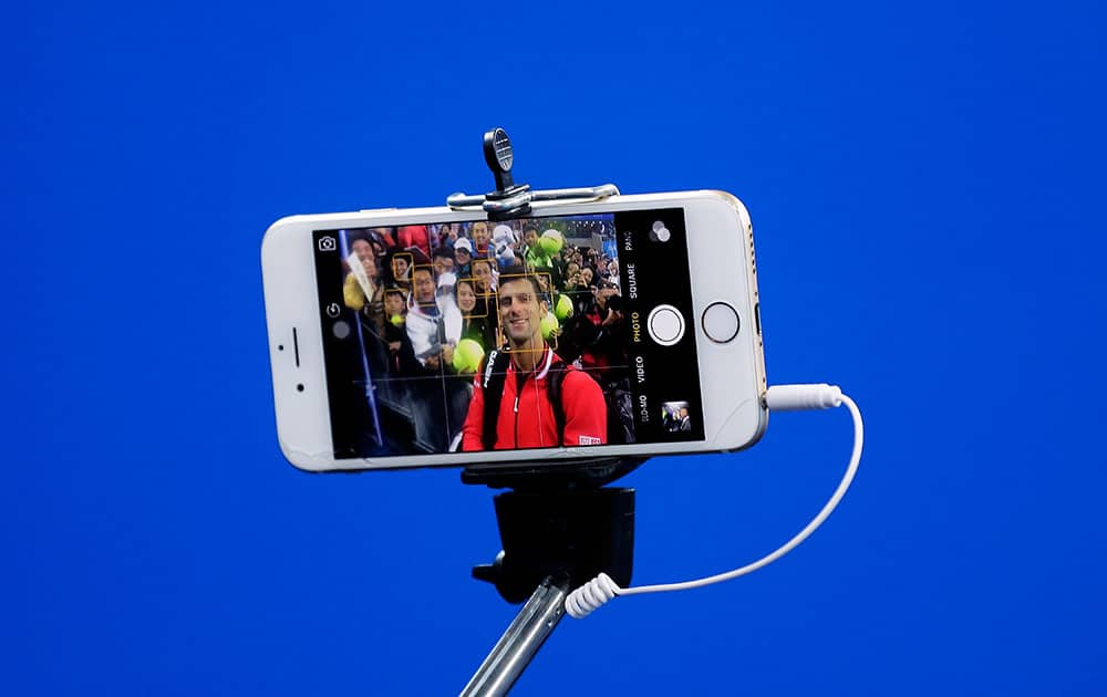 Novak Djokovic of Serbia takes a selfie with spectators after winning his men's singles quarterfinal match against John Isner of the United States in the China Open tennis tournament at the National Tennis Stadium in Beijing.