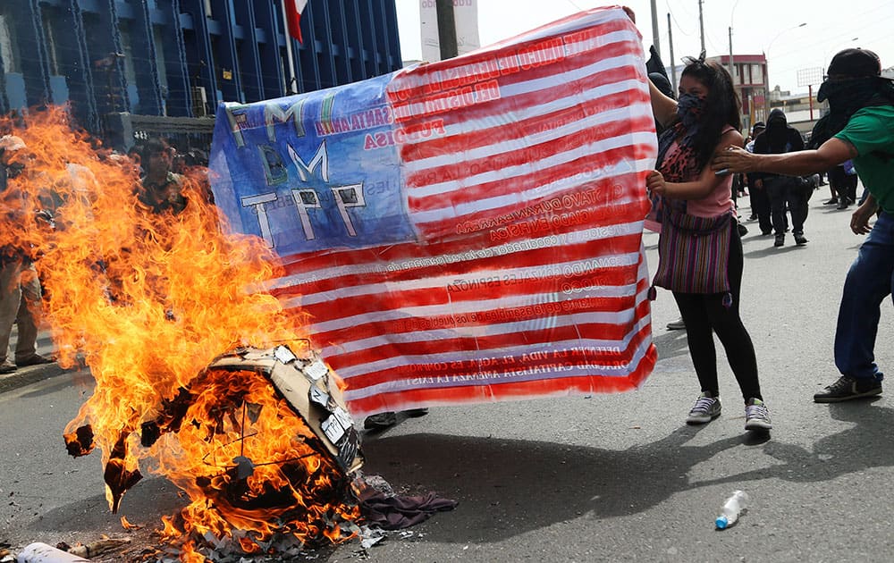 Protestors burn cardboard painted in the likeness of the US flag a few blocks from Lima Convention Center, the venue for the World Bank and IMF annual meetings in Lima, Peru.