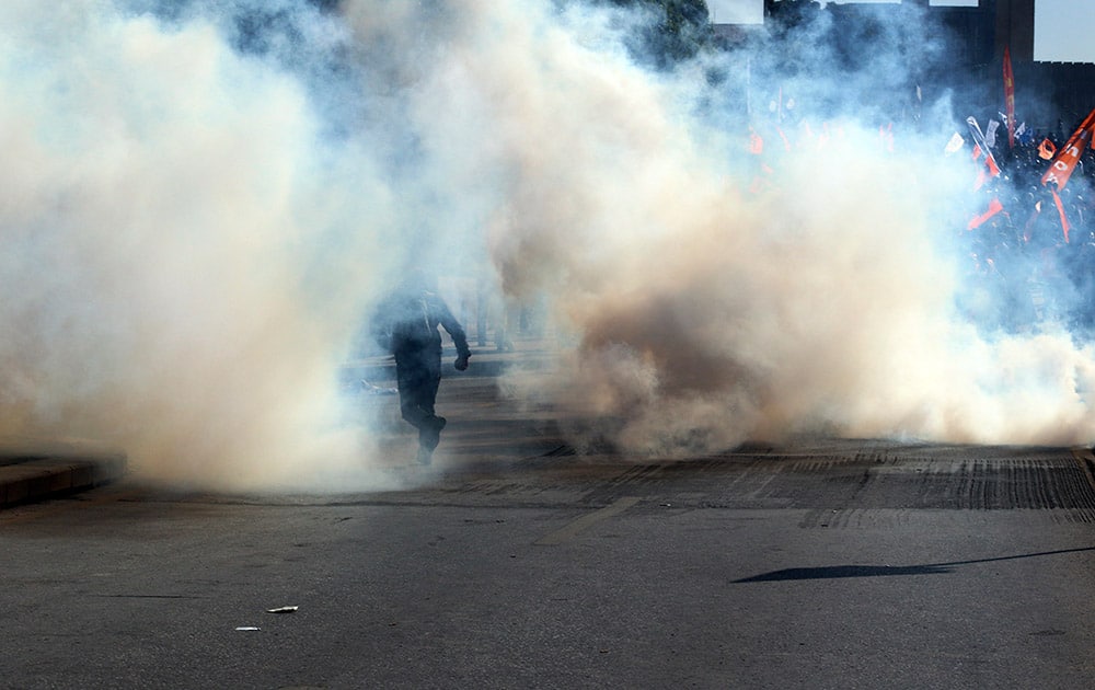 A protester runs to avoid tear gas fired by Turkish police to disperse people protesting and to open the way to ambulances near the site of an explosion in Ankara, Turkey.