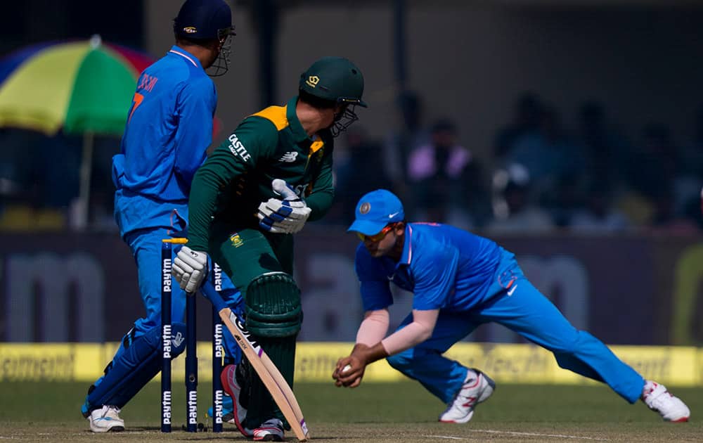 Indian cricketer Suresh Raina, right, takes a catch of South African batsman Quinton de Kock, center, as Mahendra Singh Dhoni watches, during the first of their five one-day match series in Kanpur, India.