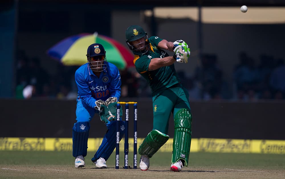 As Indian wicketkeeper Mahendra Singh Dhoni watches, South African batsman A B de Villiers hits a six while playing against India in the first of their five one-day match series in Kanpur, India.