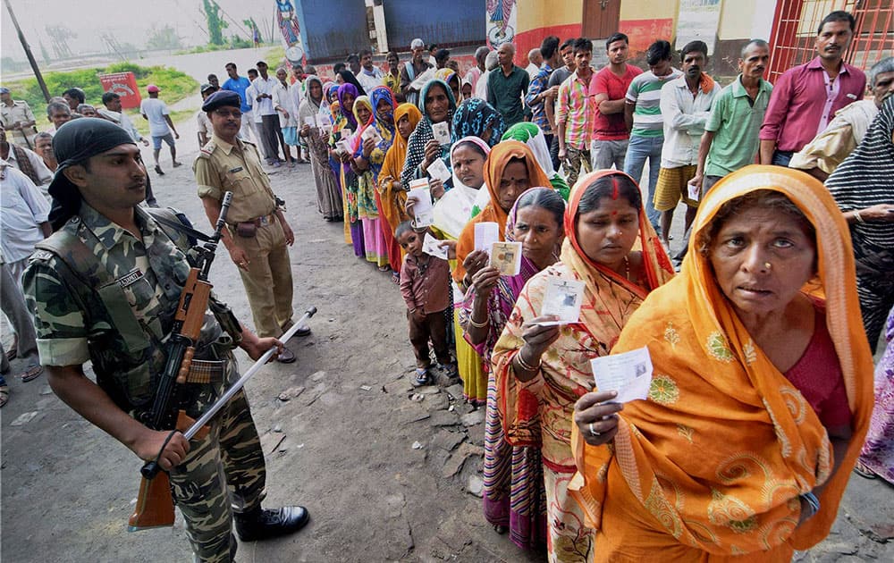 Security personnel maintaining queues of voters at a polling station during Bihar assembly elections in Begusarai.