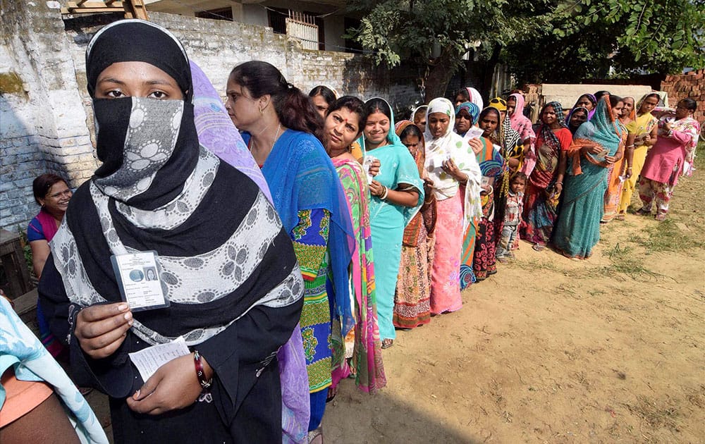 Voters wait in queues to cast their votes at a polling station in Begusarai on Monday during the first phase of Bihar assembly election.