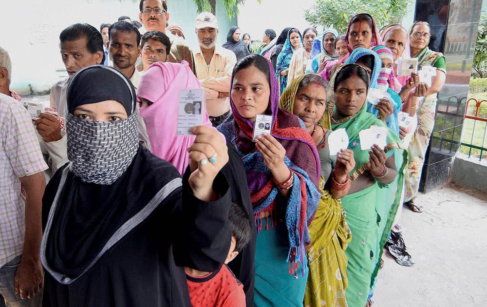 Voters wait in queues to cast their votes at a polling station in Begusarai on Monday during the first phase of Bihar assembly elections.