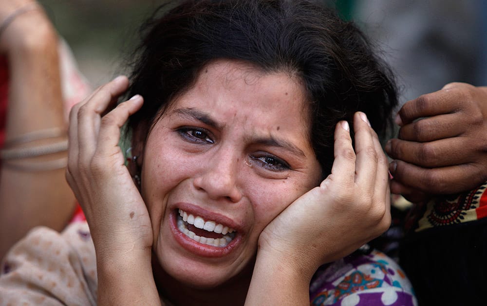 A woman mourns the death of her daughter, a victim of landslide, in Karachi, Pakistan.  Police say a landslide has hit three makeshift homes in a slum, killing more than a dozen people.