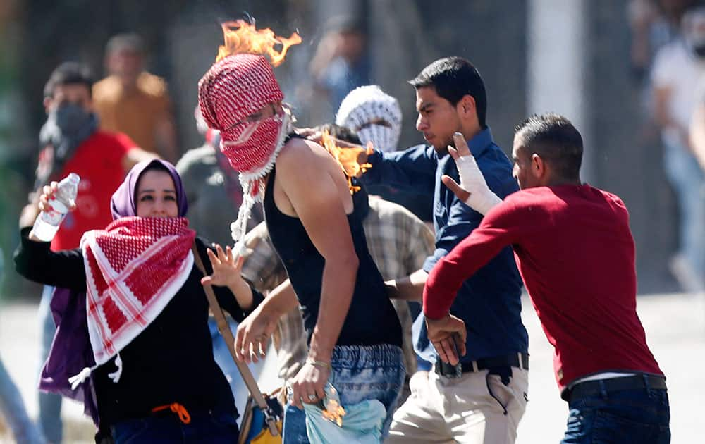 Palestinian's try to help a demonstrator who accidentally set his scarf on fire during clashes with Israeli troops in the West Bank city of Hebron. 