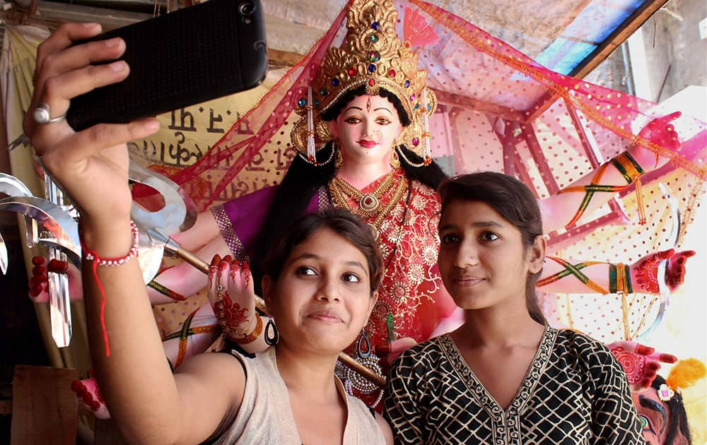 Girls clicking selfie with Goddess Durga idol on the occasion of Durga Puja Festival at Chitaroli in Nagpur, Maharashtra.