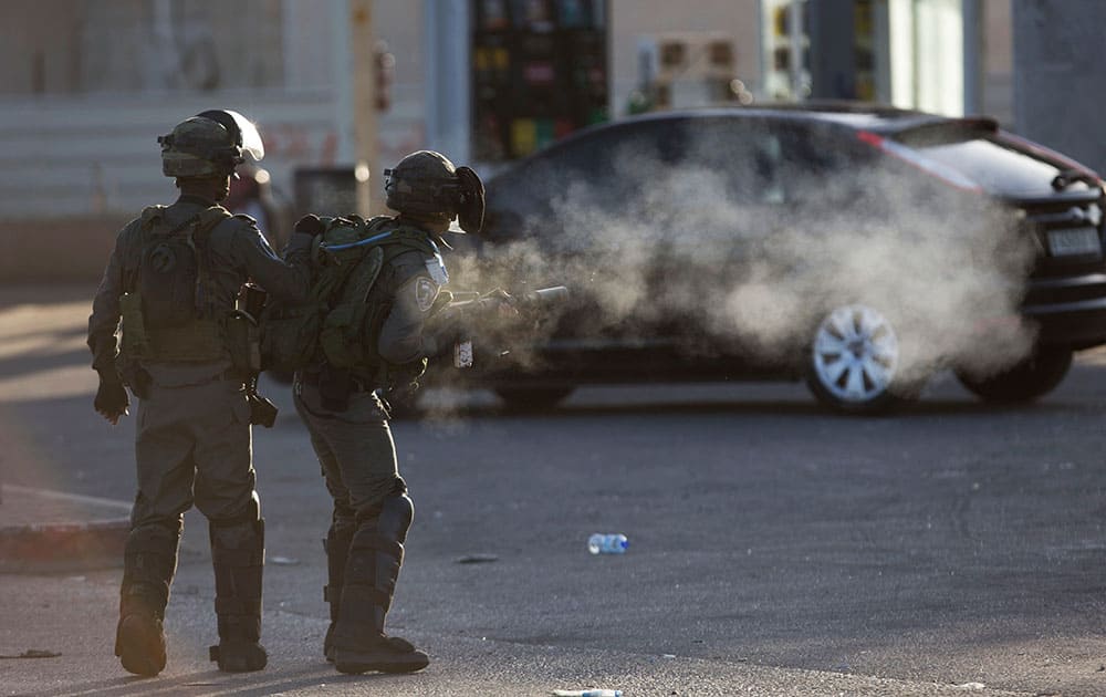 An Israeli border policeman fires rubber bullets during clashes with Palestinian protesters near Ramallah.