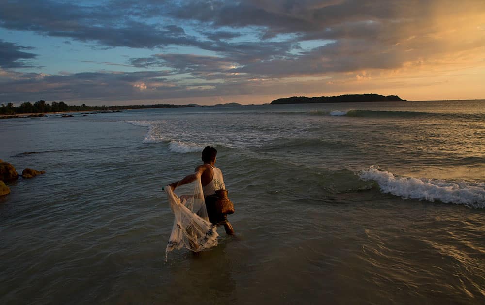 A fisherman throws a net to catch fish in the shallow waters of Ngapali beach in Myanmar's western Rakhine State at dusk.