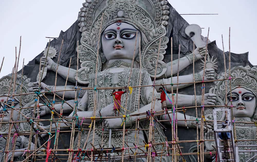 Workers on a bamboo scaffold give finishing touches to a huge idol of Hindu Goddess Durga at a worship venue in Kolkata.