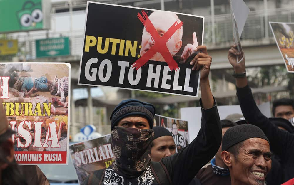 A masked Muslim man holds up a defaced poster of Russian President Vladimir Putin during a protest outside the Russian Embassy in Jakarta, Indonesia. Dozens of Muslim hardliners staged the protest against Russia's military intervention in Syria.