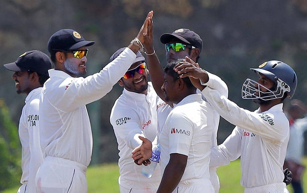 Sri Lankan cricketers congratulate bowler Rangana Herath, without cap, for the dismissal of West Indies Kemar Roach during the fourth day of the first test cricket match in Galle, Sri Lanka.