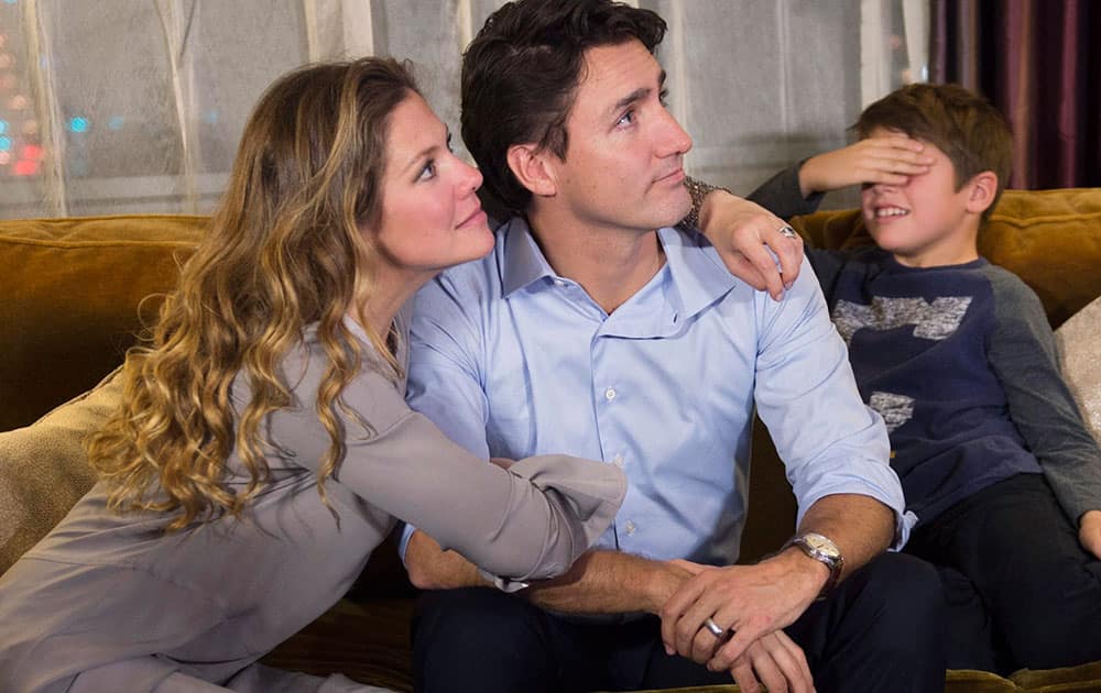 Xavier Trudeau, right, covers his eyes as Liberal leader Justin Trudeau watches the election results with his wife Sophie Gregoire at a hotel in downtown Montreal.