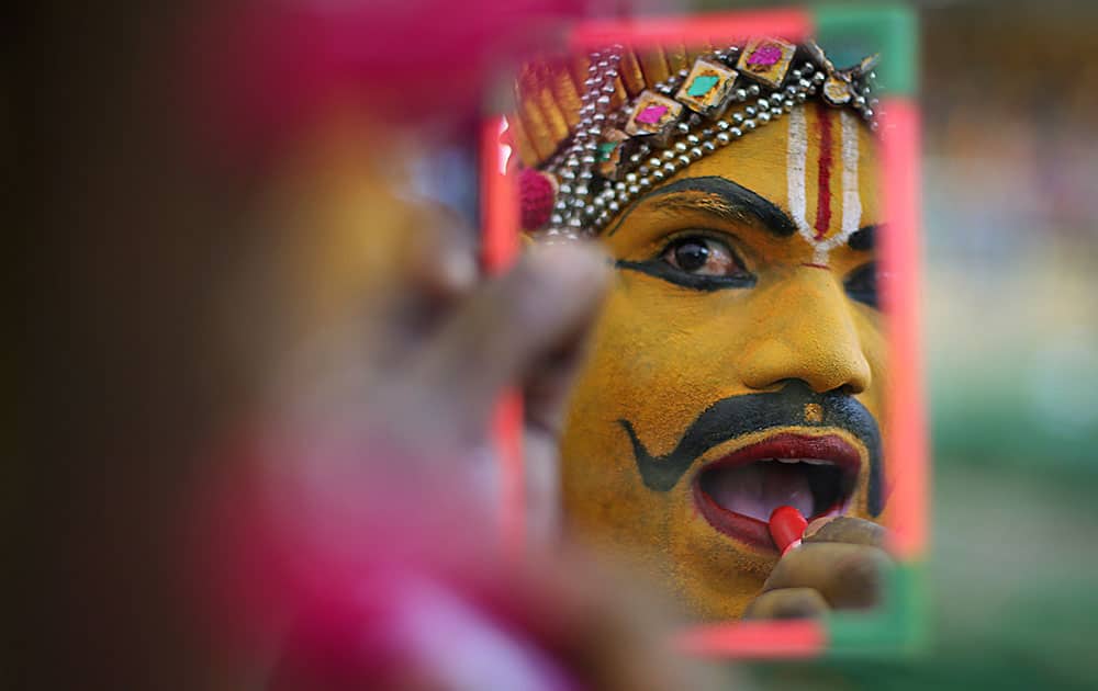 An artist applies makeup as he gets ready to perform during the Bathukamma festival dedicated to the Hindu Goddes Gauri in Hyderabad.