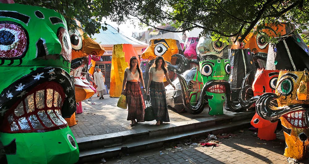 Girls walk past effigies of demon king Ravana displayed for sale at a roadside ahead of Hindu festival Dussehra in New Delhi.