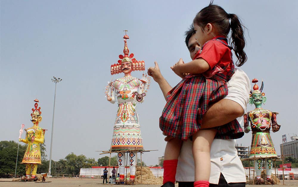 A father showing his daughter effigies of evil King Ravan, Kumbhakaran and Meghnad at Kasturchand Park on the eve of Dussehra Festival in Nagpur.