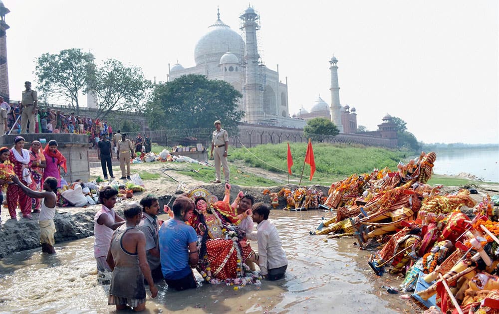 Devotees immersing an idol of Goddess Durga near Taj Mahal in Agra .