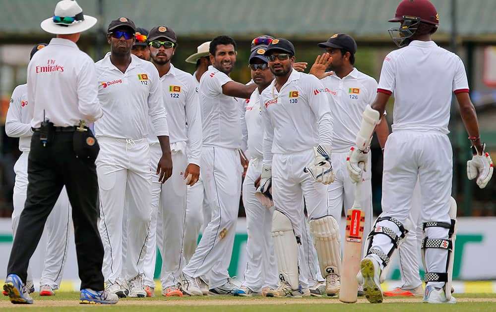 Sri Lanka’s cricket team members congratulate Dhammika Prasad, center, for the dismissal of West Indies' Darren Bravo on the second day of their second test cricket match in Colombo, Sri Lanka.
