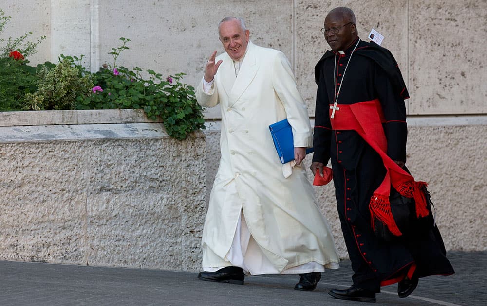 Pope Francis arrives with Cardinal Philippe Nakellentuba Ouedraogo to attend the morning session of the Synod of bishops at the Vatican.