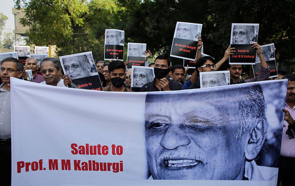 Writers and cultural activists wear black cloth over their mouths as they carry placards and a banner during a silent protest march outside Sahitya Akademi in New Delhi.