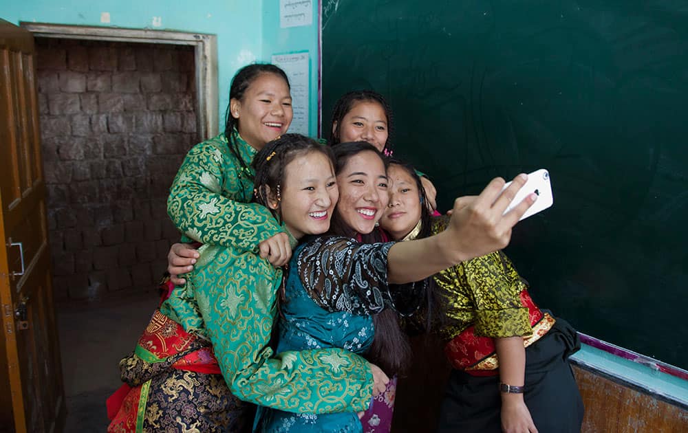 Exile Tibetan school students in traditional attire take a selfie with their instructor, as they wait to perform a song during the Founding Anniversary celebrations of the Tibetan Children's Village School in Dharmsala.