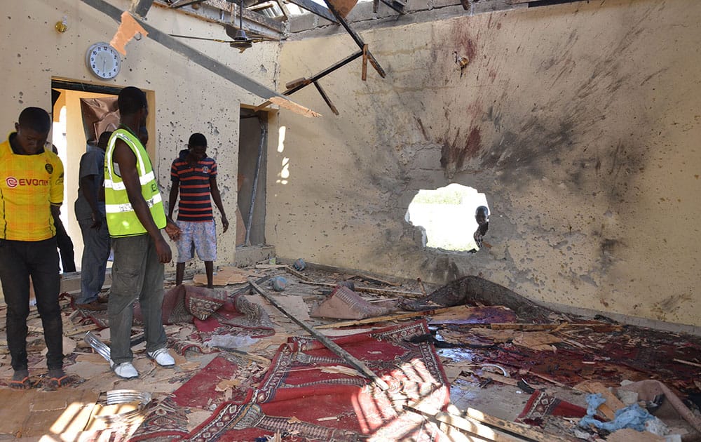 People inspect a damaged mosque following an explosion in Maiduguri, Nigeria. A self-defense fighter says twin bomb blasts have killed at least 18 at a northeast Nigerian mosque crowded with people observing pre-dawn prayers.