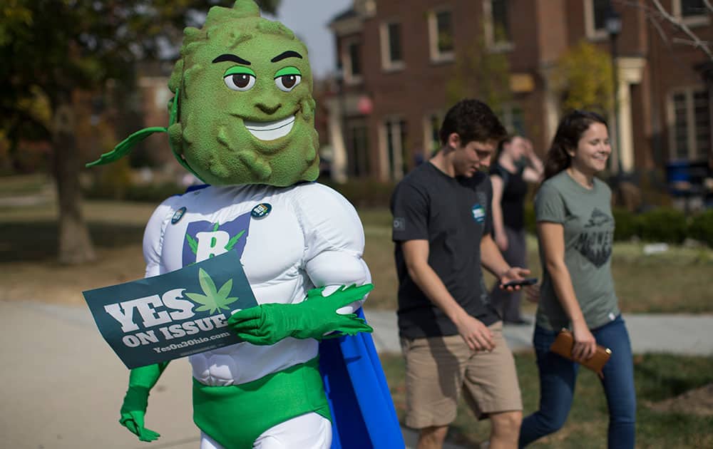 Buddie, the mascot for the pro-marijuana legalization group ResponsibleOhio, waits on a sidewalk to greet passing college students during a promotional tour bus at Miami University.