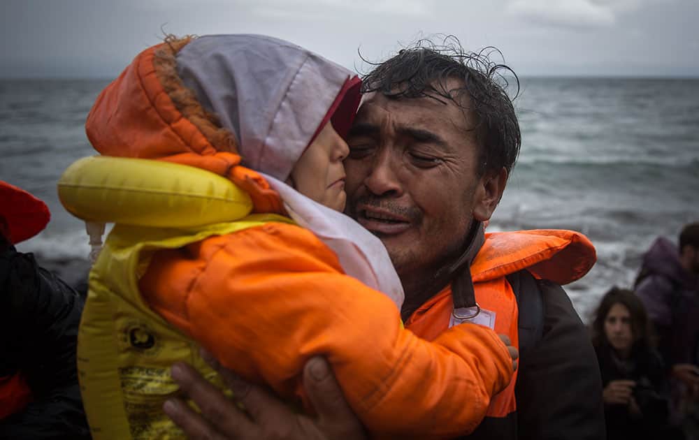 A man hugs a child on a beach after arriving with other migrants and refugees in a dinghy from the Turkish coast to the Skala Sikaminias village on the northeastern Greek island of Lesbos.