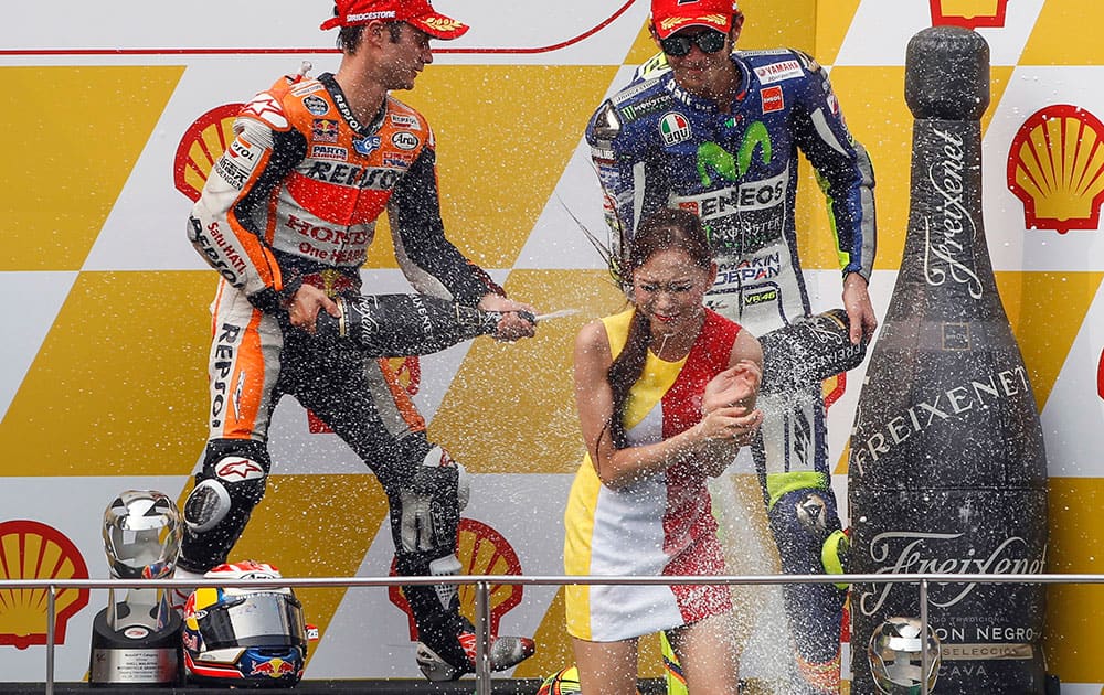 MotoGP rider Dani Pedrosa, left, of Spain and Valentino Rossi, right, of Italy spray champagne on an usherette during the awards ceremony of Malaysian Motorcycle Grand Prix in Sepang, Malaysia.
