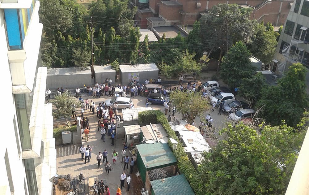 People stand after they rushed out of buildings as a strong tremor was felt in Noida.