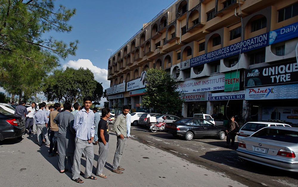 People stand outside their offices after a severe earthquake is felt in Islamabad, Pakistan.