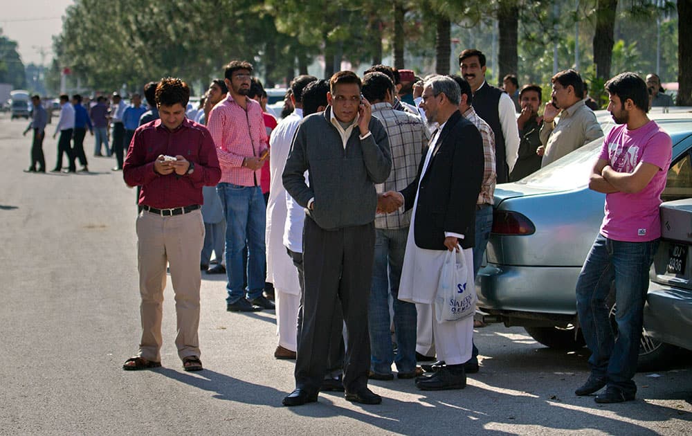 People stand outside their offices after a severe earthquake is felt in Islamabad, Pakistan.