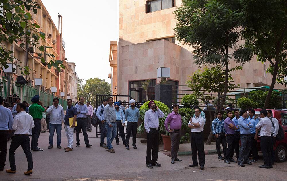 People stand after they rushed out of buildings as a strong tremor was felt in New Delhi.