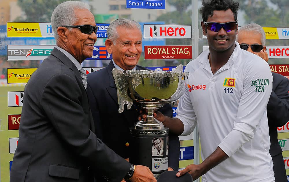 Sri Lanka's captain Angelo Mathews receives the series trophy from West Indies great Garfield Sobers and Michael Tissera, a national captain in Sri Lanka's pre-test era after Sri Lanka defeated West Indies in the second test cricket match in Colombo, Sri Lanka.