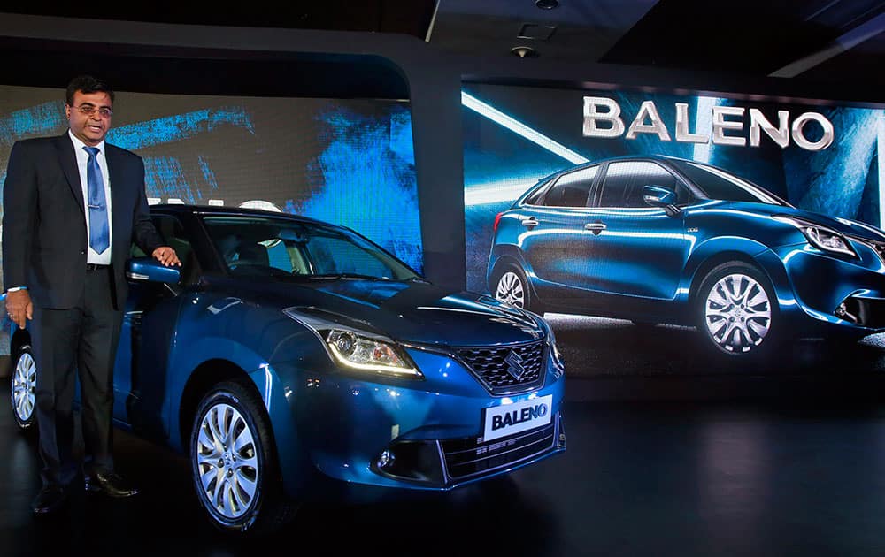 Partho Banerjee Vice President Sales and Dealer Network of Maruti Suzuki poses next to the newly-unveiled Baleno hatchback during its global launch in Mumbai.