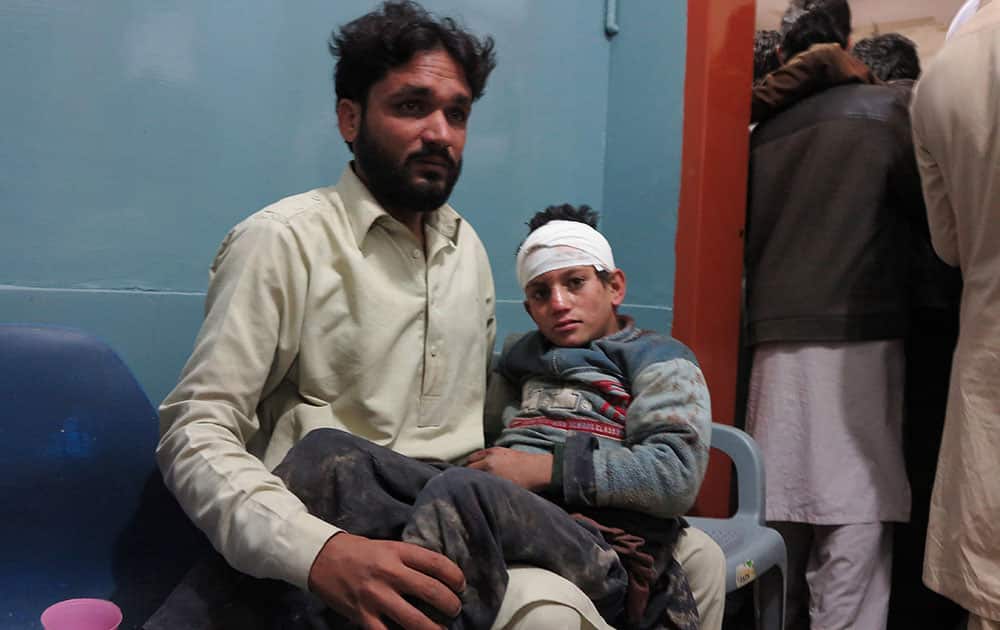 A Pakistani man holding his son waits for medical help at a local hospital in Mingora, Pakistan. A powerful 7.7-magnitude earthquake in northern Afghanistan rocked cities across South Asia.
