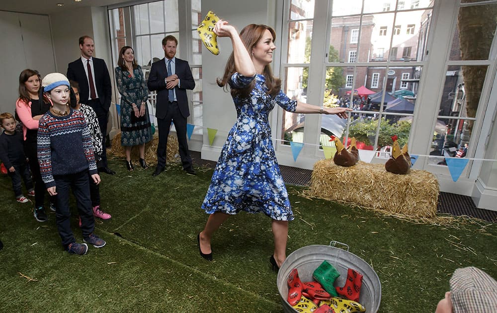 Britains Kate, Duchess of Cambridge takes part in welly wanging, watched by the Duke of Cambridge, back left, and Prince Harry, centre, with children and representatives from charities and Aardman Animations, during a meeting of the Charities Forum at BAFTA on Piccadilly in London.