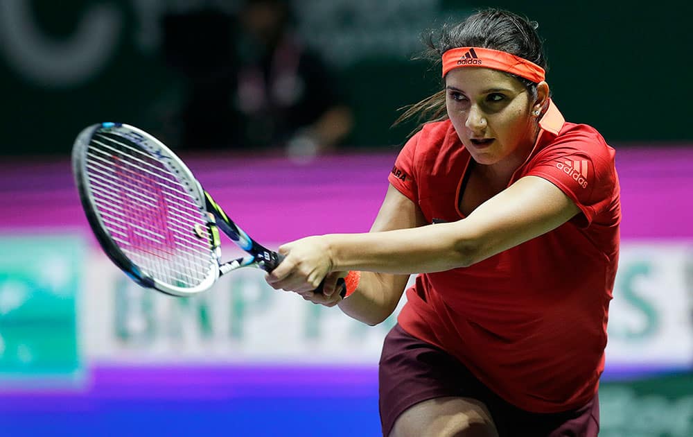 Sania Mirza of India, watches her return as she pairs up with partner Martina Hingis of Switzerland, during their doubles match against Raquel Kops-Jones and Abigail Spears of the United States at the WTA tennis finals in Singapore.