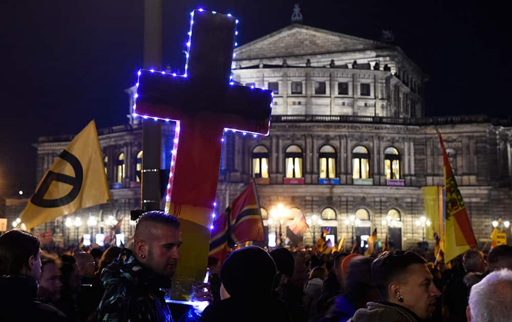 A man holds a illuminated cross in German national colors as he attends a demonstration of the PEGIDA (Patriotic Europeans against the Islamization of the West), in front the Semperoper opera house in Dresden.