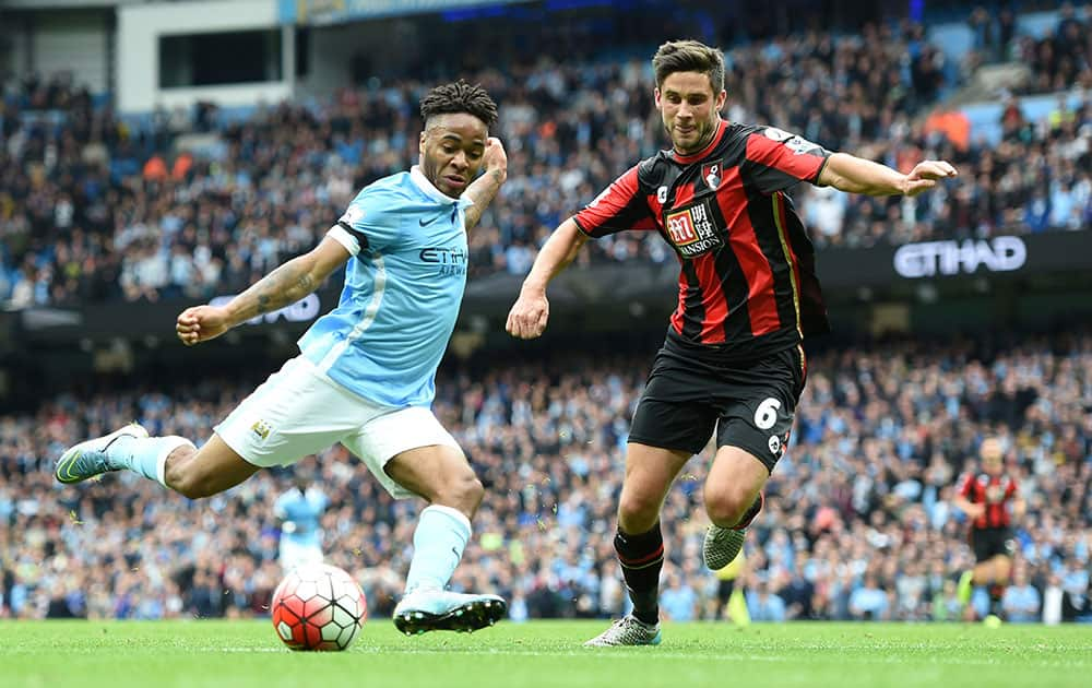 Manchester City's Raheem Sterling, left, scores his side's fourth goal of the game to complete his hat-trick, past Bournemouth's Andrew Surman, during their English Premier League soccer match at The Etihad Stadium, Manchester, England.