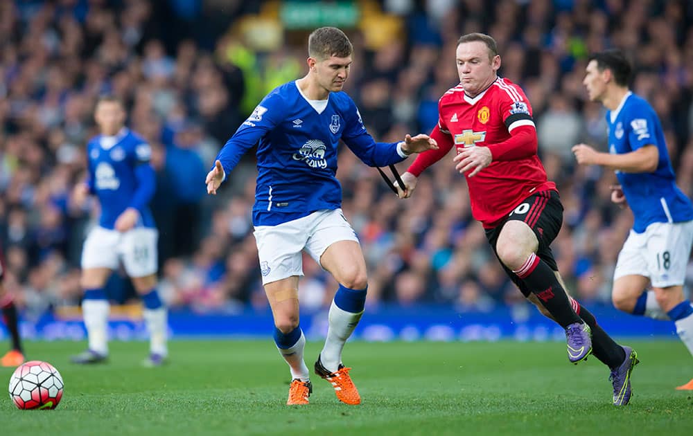 Manchester United's Wayne Rooney, centre right, grabs a hold of Everton's John Stones during the English Premier League soccer match between Everton and Manchester United at Goodison Park Stadium, Liverpool, England.