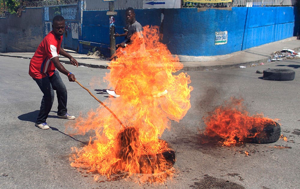 A protester supporter of presidential candidate Moise Jean-Charles, of the Platform Pitit Dessalines political party sets fire to a tire during a protest in Port-au-Prince, Haiti.