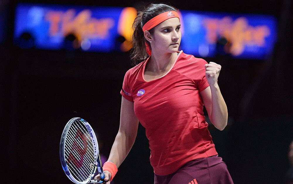 Sania Mirza of India celebrates winning a set with her partner Martina Hingis of Switzerland as they play Timea Babos of Hungary and Kristina Mladenovic of France during their doubles match at the WTA tennis finals in Singapore.