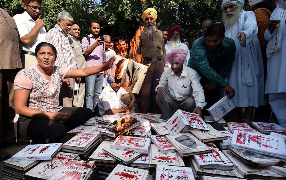 An author along with supporters burning the copies of his book, which has been banned since 1998, during a protest against the injustice at Jantar Mantar, in New Delhi.