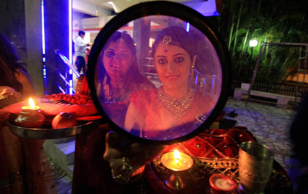 Married women look at the moon through a sieve as part of a ritual to break fast during Karva Chauth festival.