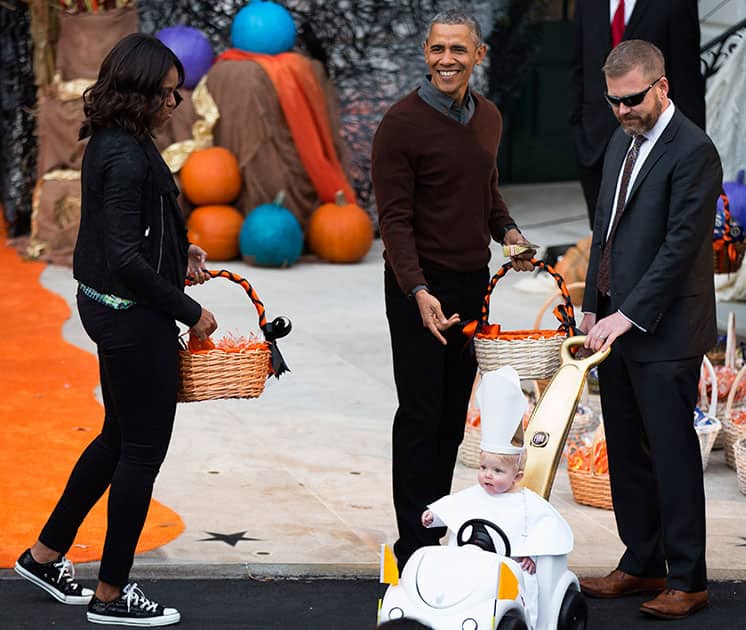 President Barack Obama and first lady Michelle Obama, left, greets a child dressed as the pope during Halloween festivities at the South Portico of the White House in Washington.